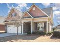 Traditional brick home with attached garage and covered front porch featuring rocking chairs at 231 Easy Wind Ln, Garner, NC 27529