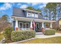 Charming blue home with a inviting front porch, white columns and meticulously maintained landscaping at 332 Pine Nut Ln, Apex, NC 27502