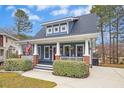 Charming blue home with a inviting front porch, white columns and meticulously maintained landscaping at 332 Pine Nut Ln, Apex, NC 27502