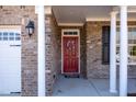 Close-up of a red front door with a decorative wreath, flanked by white columns and black shutters at 430 Easy Wind Ln, Garner, NC 27529