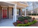 Inviting front porch with white columns, brick facade, and colorful landscaping with flowers and shrubbery at 430 Easy Wind Ln, Garner, NC 27529