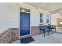 Cozy front porch with seating, featuring a charming blue door and brick detailing at 505 Ferry Ct, Wake Forest, NC 27587