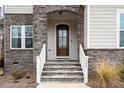 Elegant stone entryway leading to a wood front door, accented by white railings and house number at 664 The Parks Dr, Pittsboro, NC 27312