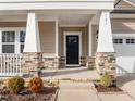 Inviting front porch with stone accents and white pillars creates a warm entry at 721 Sage Oak Ln, Holly Springs, NC 27540