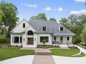 Charming white brick home featuring a gray shingle roof, black framed windows and a landscaped front yard at 7217 Manor Oaks Dr, Raleigh, NC 27615