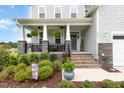 Inviting covered front porch with brick steps, stone accents, and beautifully landscaped garden at 1001 Peterson Ridge Rd, Fuquay Varina, NC 27526