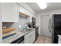 Galley kitchen with stainless steel appliances, granite countertops, gray backsplash, and wood-look floors at 1110 Schaub Dr # B, Raleigh, NC 27606
