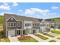 Row of townhomes featuring gray and white exteriors, well-kept lawns, and individual driveways under a sunny sky at 120 Central Townes Way # 292, Raleigh, NC 27603