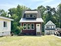 A small home with craftsman trim, a metal roof and a neatly manicured lawn is nestled in a wooded lot at 1448C Maplewood Dr, Durham, NC 27704