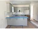 Modern kitchen featuring gray cabinets, white subway tile backsplash, and a breakfast bar with protective blue covering at 1448C Maplewood Dr, Durham, NC 27704
