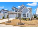 Beautifully landscaped two-story home with stone accents, light blue siding, and a two-car garage at 163 Auburn Village Blvd, Raleigh, NC 27610