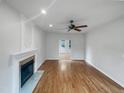 Open-concept living room featuring a fireplace, ceiling fan, and beautiful hardwood floors at 1908 Mystic Dr, Durham, NC 27712