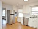 Well-lit kitchen featuring stainless steel appliances, white cabinets, and vinyl floors at 215 Sallinger St, Knightdale, NC 27545