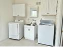 Bright laundry room with white washer, dryer, sink and storage cabinets at 215 Sallinger St, Knightdale, NC 27545