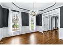 Dining room featuring wainscoting, hardwood floors, a chandelier, and large windows with curtains at 521 Lyndenbury Dr, Apex, NC 27502