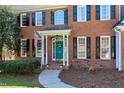 A lovely two-story brick home, featuring a teal front door and black window shutters at 521 Lyndenbury Dr, Apex, NC 27502