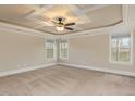 Bright bedroom featuring neutral walls, a trey ceiling with fan, and multiple windows offering abundant natural light at 6712 Stepherly Way, Holly Springs, NC 27540