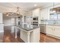 Open kitchen with white cabinets, stainless appliances, and a granite island flowing into a living space with trey ceilings at 6712 Stepherly Way, Holly Springs, NC 27540