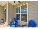 Cozy covered front porch with blue Adirondack chairs and a view through a large window at 86 Cecina Ct, Clayton, NC 27527