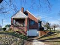 Brick home showcasing a back porch, stairs to the garage, and a well-maintained yard with mature trees at 1006 Stallings Rd, Durham, NC 27703
