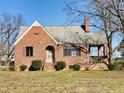 Inviting one-story brick home featuring a covered porch and well-manicured landscaping on a sunny day at 1006 Stallings Rd, Durham, NC 27703