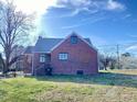 Rear view of a well-maintained brick home with a lush green yard and mature trees under a sunny sky at 1006 Stallings Rd, Durham, NC 27703