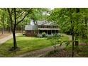 Two-story brick home with a white porch, surrounded by lush trees and a winding driveway on a sunny day at 1013 Traders Trl, Wake Forest, NC 27587