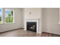 Living room featuring a fireplace with a white mantle, wood-look floors, and natural light at 120 Pisgah St, Sanford, NC 27330