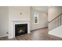 Open-concept living area with fireplace, wood-look floors, and staircase to the upper level at 120 Pisgah St, Sanford, NC 27330