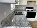Modern kitchen featuring sleek granite countertops, stainless steel sink, and ample lighting at 128 Glengariff Ln, Clayton, NC 27520