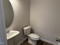 Powder room featuring wood flooring, a pedestal sink, and a toilet at 131 E Victory View. Ter, Smithfield, NC 27577