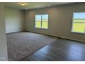 A spacious living room featuring both carpet and wood flooring and multiple windows with outdoor views at 131 E Victory View. Ter, Smithfield, NC 27577