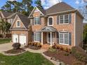 Charming brick home featuring a two-car garage, mature landscaping, and an inviting entrance at 13121 Sargas St, Raleigh, NC 27614
