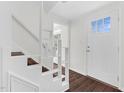 Bright entryway featuring a white door, hardwood floors, and open stairs at 2321 Ravenhill Dr, Raleigh, NC 27615