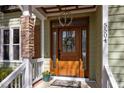 Elegant front entrance with a decorative wreath, stone pillar, and modern light fixture at 5504 Quails Call Ct, Garner, NC 27529