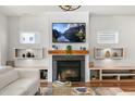 Living room fireplace with TV, built-in shelving, and modern decor at 625 Sage Oak Ln, Holly Springs, NC 27540