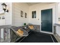 Cozy front porch with decorative chairs and a dark teal front door at 625 Sage Oak Ln, Holly Springs, NC 27540