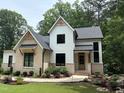 Attractive two-story home with white siding, brick accents, black trim windows, and meticulous landscaping at 6816 Rainwater Rd, Raleigh, NC 27615