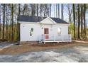 Cozy white cottage-style home with red front door surrounded by pine trees, offers a peaceful retreat at 1031 W Murray Ave, Durham, NC 27704