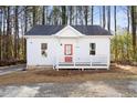 Charming white cottage-style house with a red front door, a small porch and nestled among tall pine trees at 1031 W Murray Ave, Durham, NC 27704