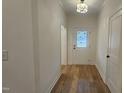 Bright hallway with hardwood floors, white walls, a modern light fixture, and a white back door at 105 Leisure Ln, Louisburg, NC 27549