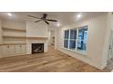 Spacious living room featuring hardwood floors, a fireplace, built-in shelves, and a large window at 105 Leisure Ln, Louisburg, NC 27549