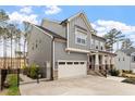 Side view of a gray two-story home showing the garage and landscaped yard at 105 Mystic Quartz Ln, Holly Springs, NC 27540