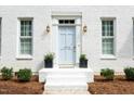 Elegant front entrance with powder blue door, decorative columns, and lush landscaping at 1222 Dixie Trl, Raleigh, NC 27607