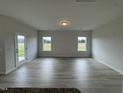 Living room with light gray wood-look flooring, windows, and neutral-painted walls at 184 Bruce Dr, Dunn, NC 28334