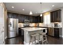 Modern kitchen with dark wood cabinets, stainless steel appliances, a granite island, and stylish pendant lighting at 1965 Drumlin Dr, Apex, NC 27502