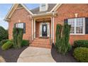 Welcoming brick front entrance with decorative glass door, manicured bushes and iron railings at 4017 Olde Waverly Way, Fuquay Varina, NC 27526
