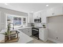 Modern kitchen with stainless steel appliances, white cabinets, and a window overlooking a lush yard at 4307 Pope Rd, Durham, NC 27707