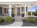 Inviting front porch with brick steps, potted plants, and white columns at 4612 Sharpecroft Way, Holly Springs, NC 27540