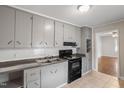 Functional kitchen featuring gray cabinets, black appliances, white tiled backsplash, and tile floors at 617 Bernice St, Durham, NC 27703
